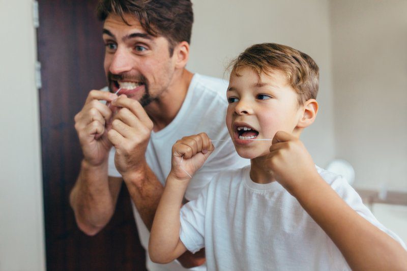 Father and son in bathroom flossing together.