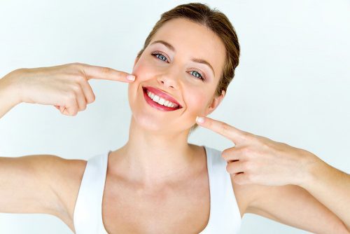 Woman pointing to her mouth with both index fingers.