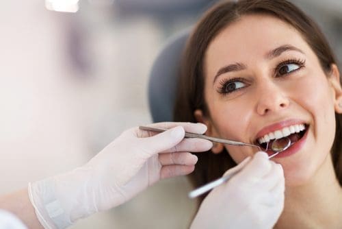 Dentist hands holding dental tools in patients mouth.