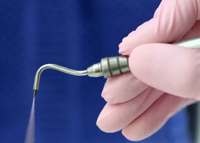 Dentist hand holding dental air pick.