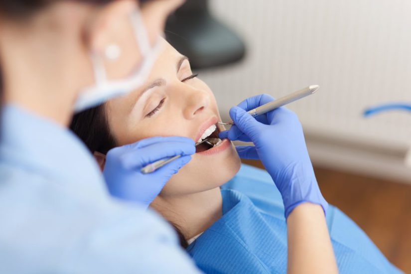 Woman in dental chair having work performed in her mouth by a dentist.