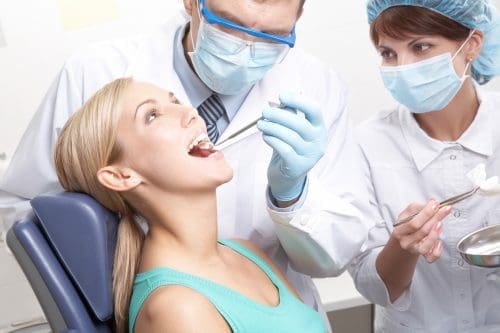 Dentist and assistant workin on patients mouth.