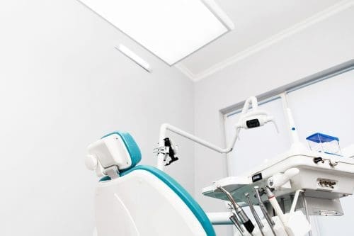 Image of dental chair and dental tools with white clinic background and bright light.