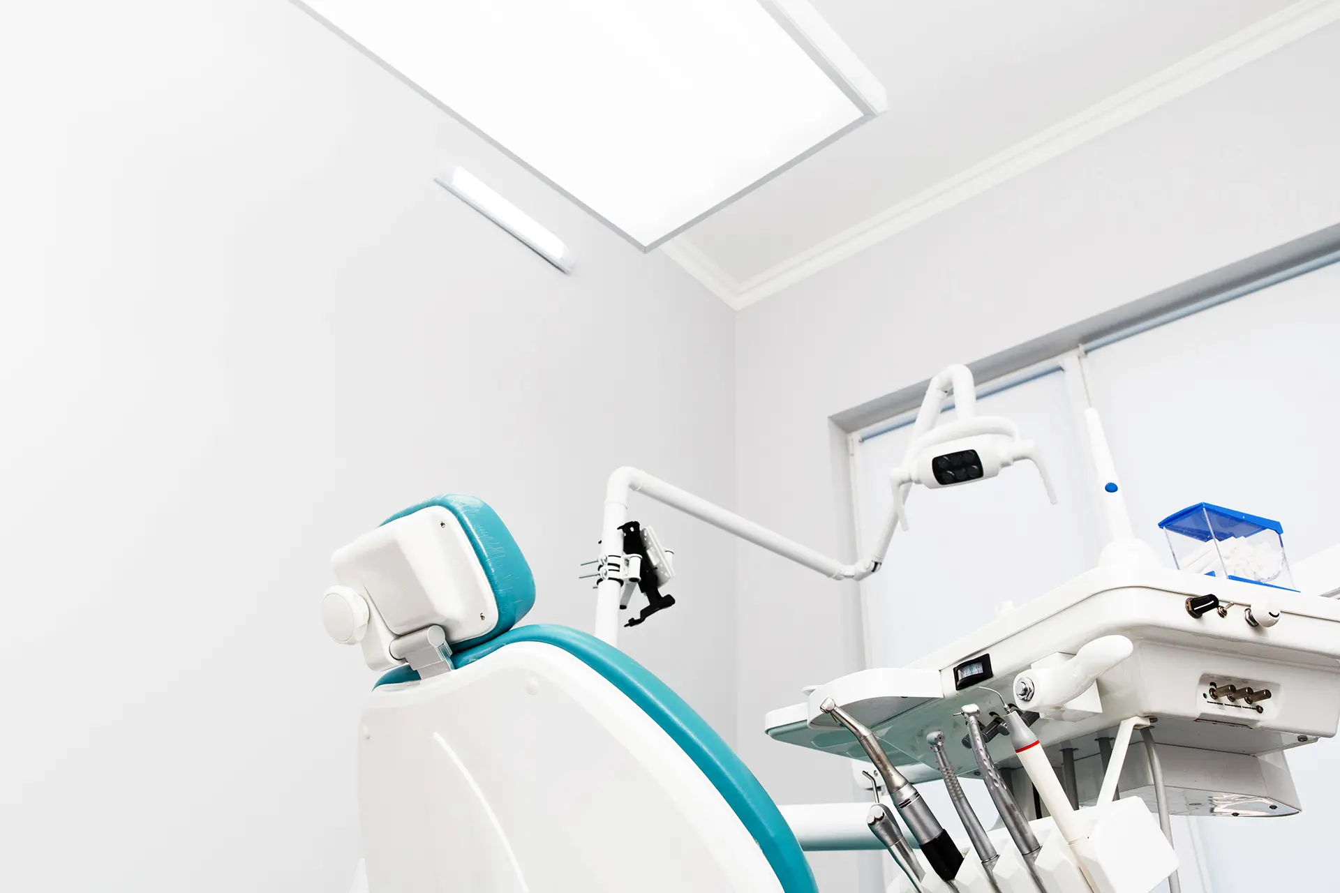 Image of dental chair and dental tools with white clinic background and bright light.