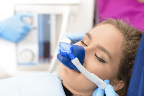 Young woman sitting on dentist chair waring a sedation nose pice.