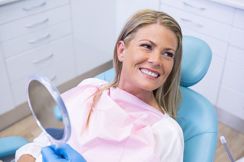 Woman sitting in dentist chair smiling.