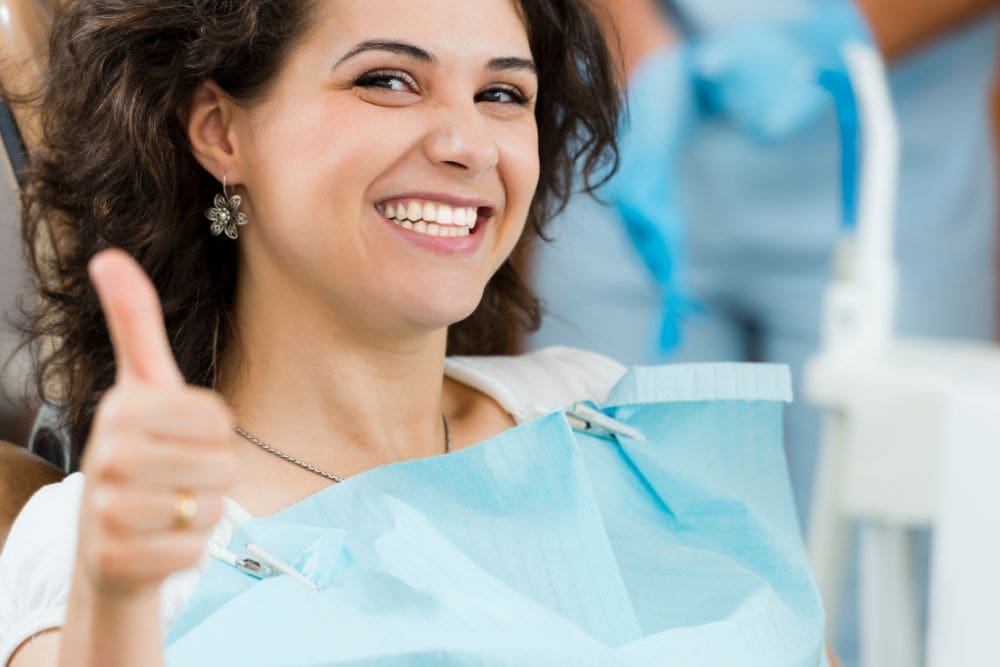 Smiling Woman in Dentist Office Gives A Thumbs Up