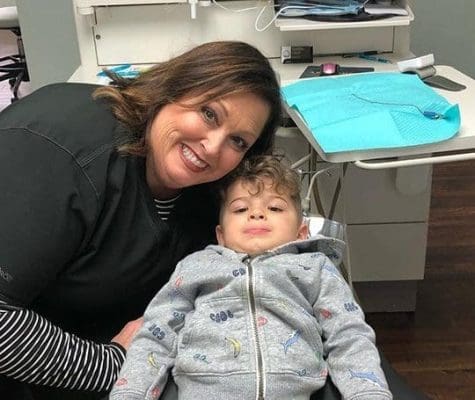 Smiling dental worker and young child at the dentist.