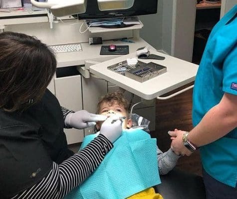 Young child on dentist chair having dental work performed.