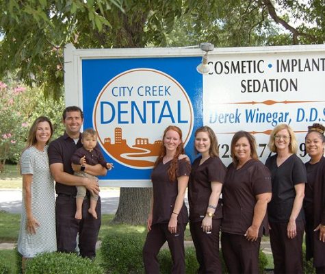 Portrait of City Creek Dental staff in front of the clinics road sign.