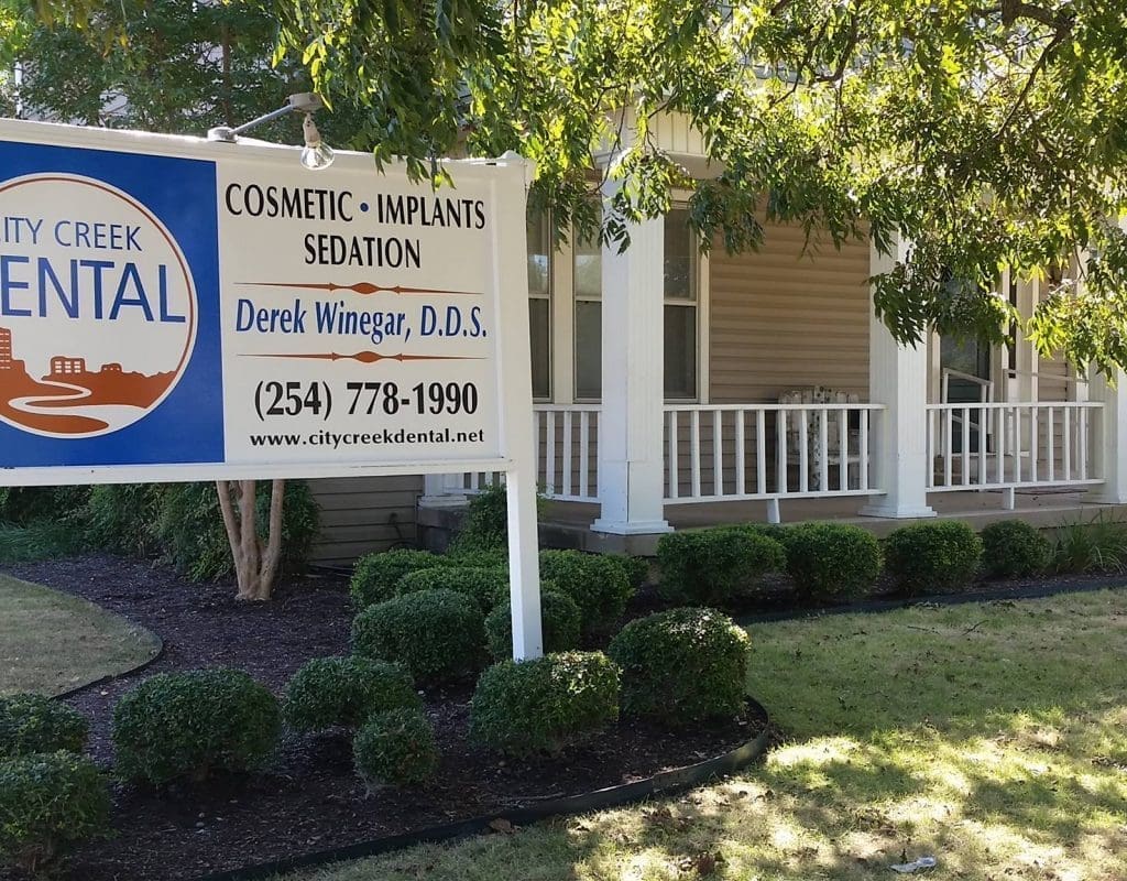 Outside Dental office with sign. Outside picture of City Creek Dental office with road sign to the left.